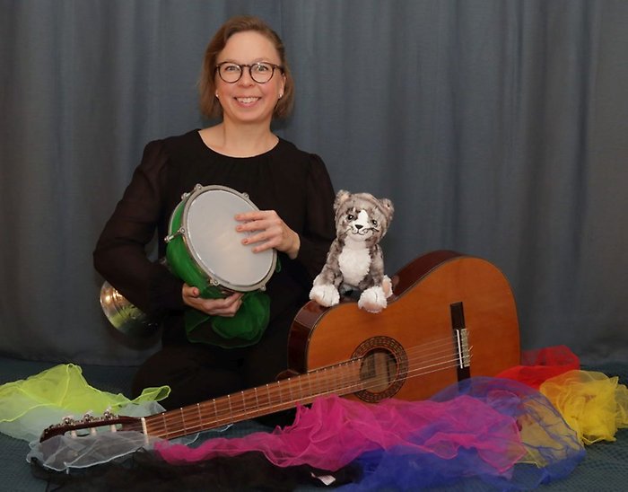 Lina Rolf sitter med sin katt och instrument.